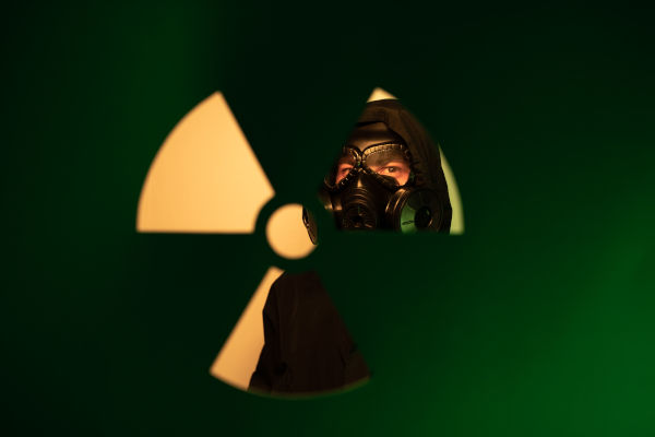 A woman peeping through the radiation exposure door with a mask on